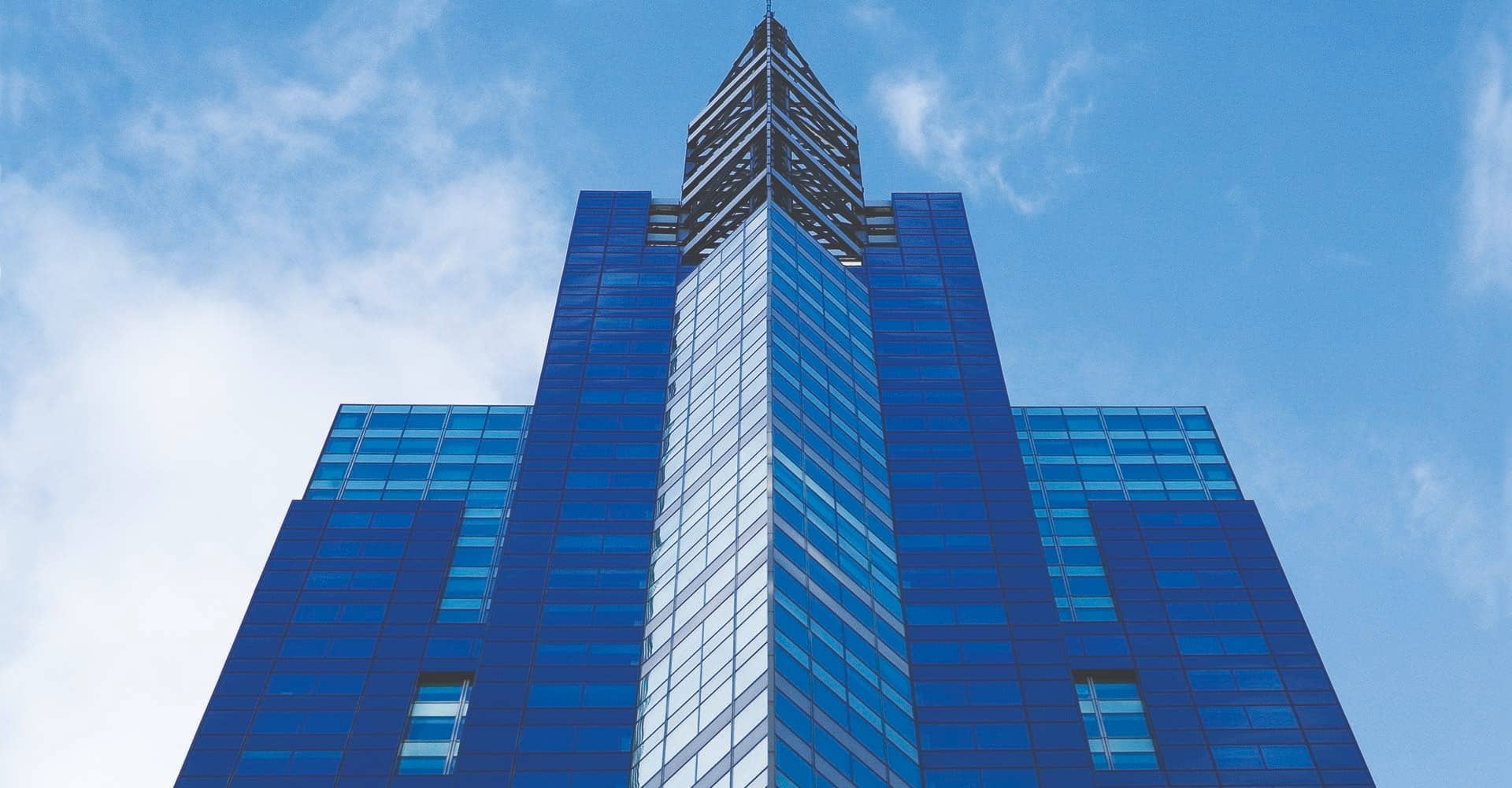 Exterior of 1540 Broadway, a blue glass office tower in Times Square, seen from below