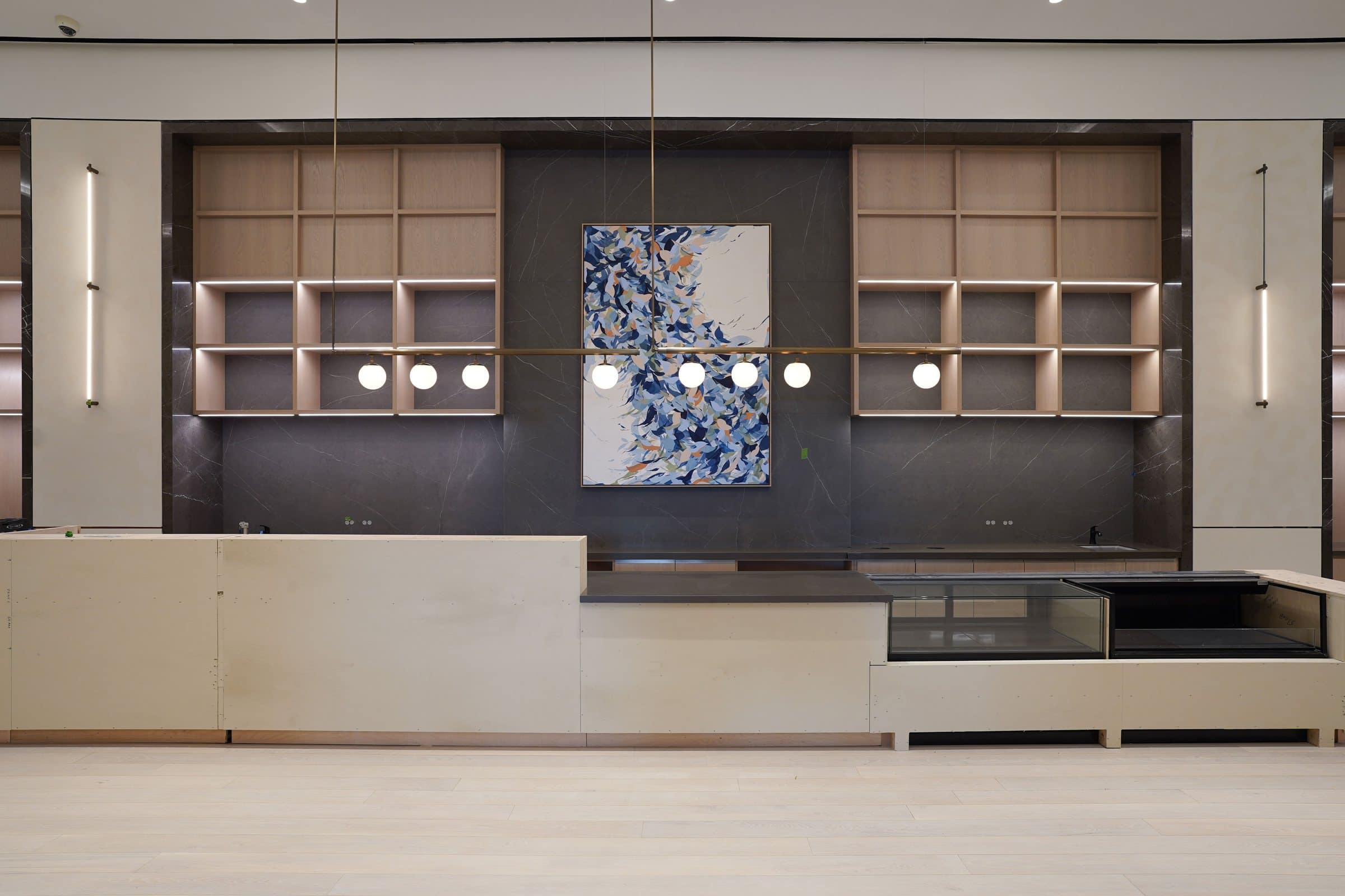 Tall blue, white and yellow gestural painting on a dark wall above an office lounge counter