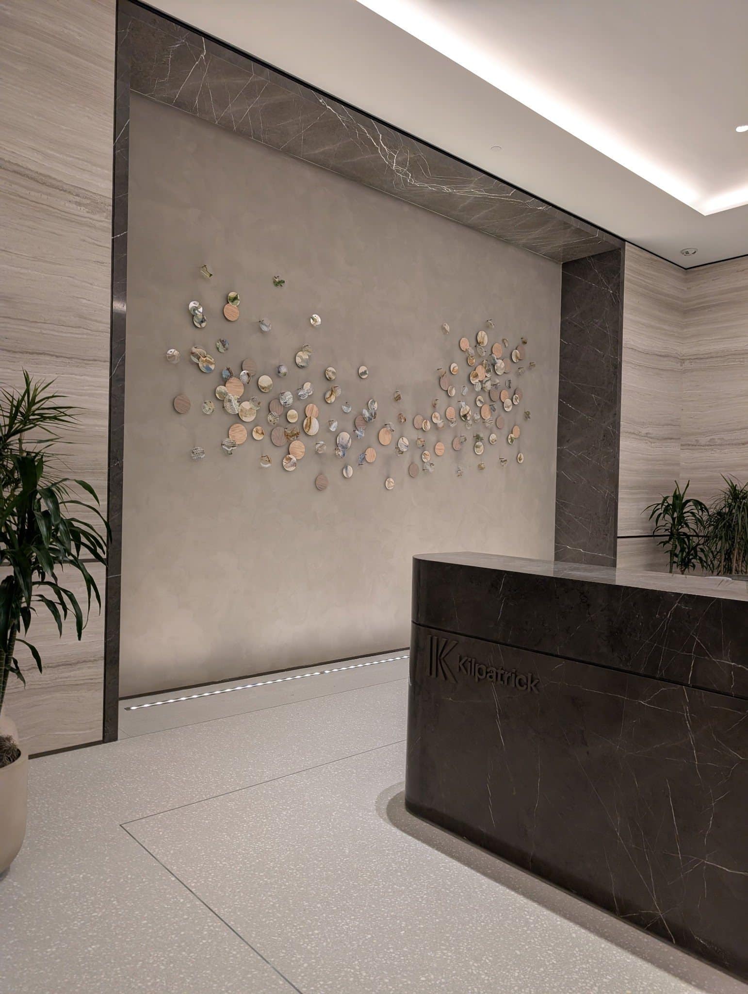 Oblique view of the circular wall installation beside the curved dark stone reception desk