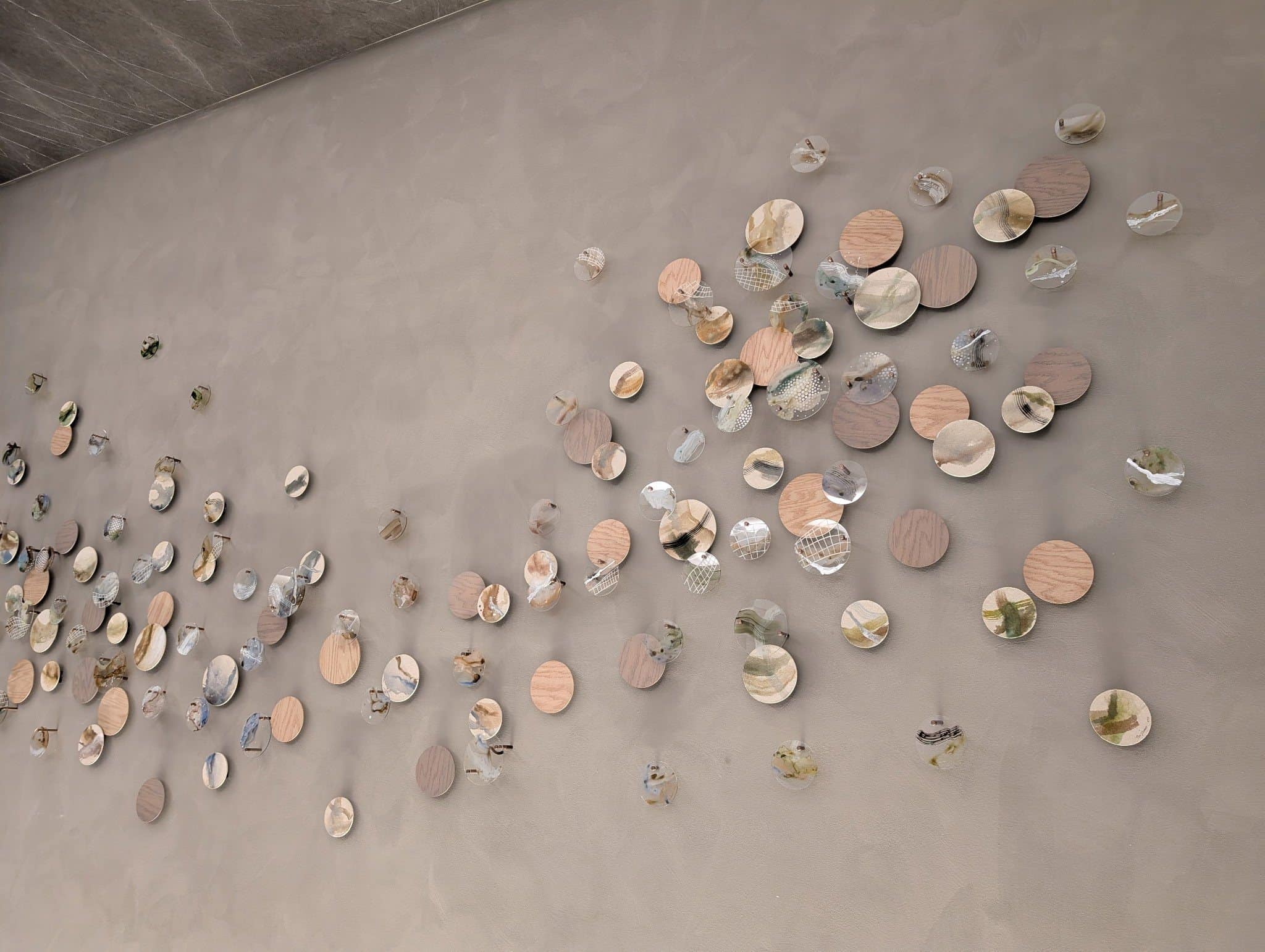 Detail of wood-toned discs and folded reflective elements scattered across the reception wall