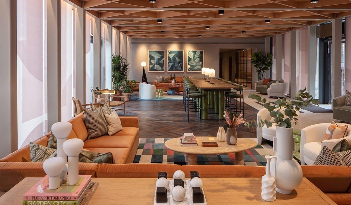 Long communal lounge with rust sofas, a dining table and three dark gestural works on the far wall