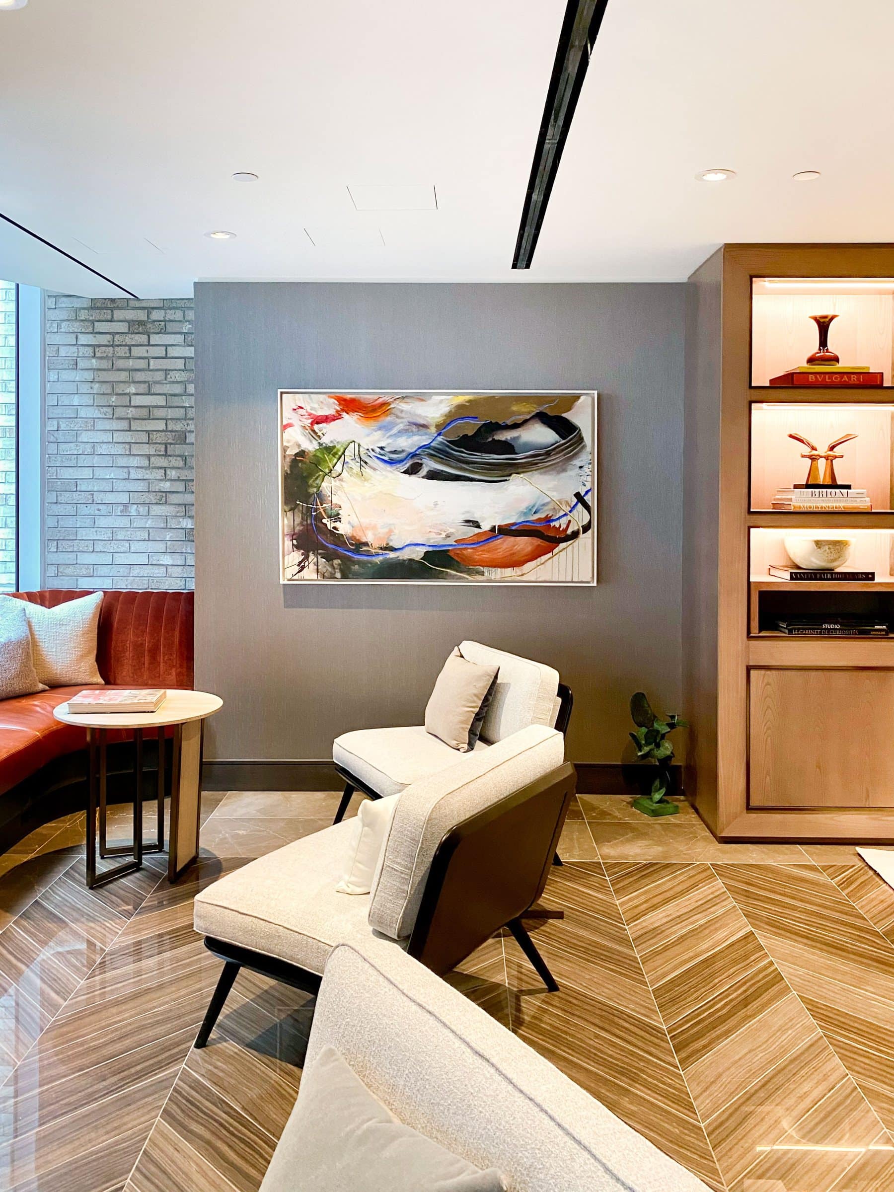 A layered gestural painting hangs above a library seating nook at Lantern House.