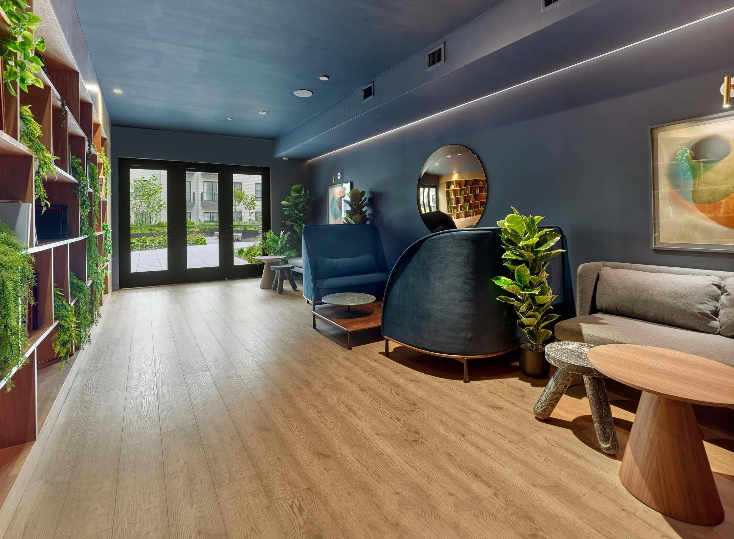 Framed art, blue lounge chairs and plants line a shared room at The Wyldes.