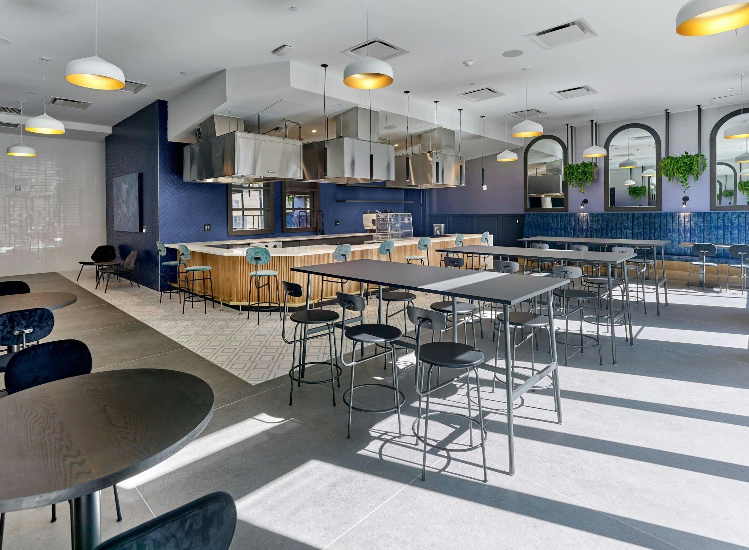 A wide view of the shared kitchen at The Wyldes shows a dark painting above seating at left.