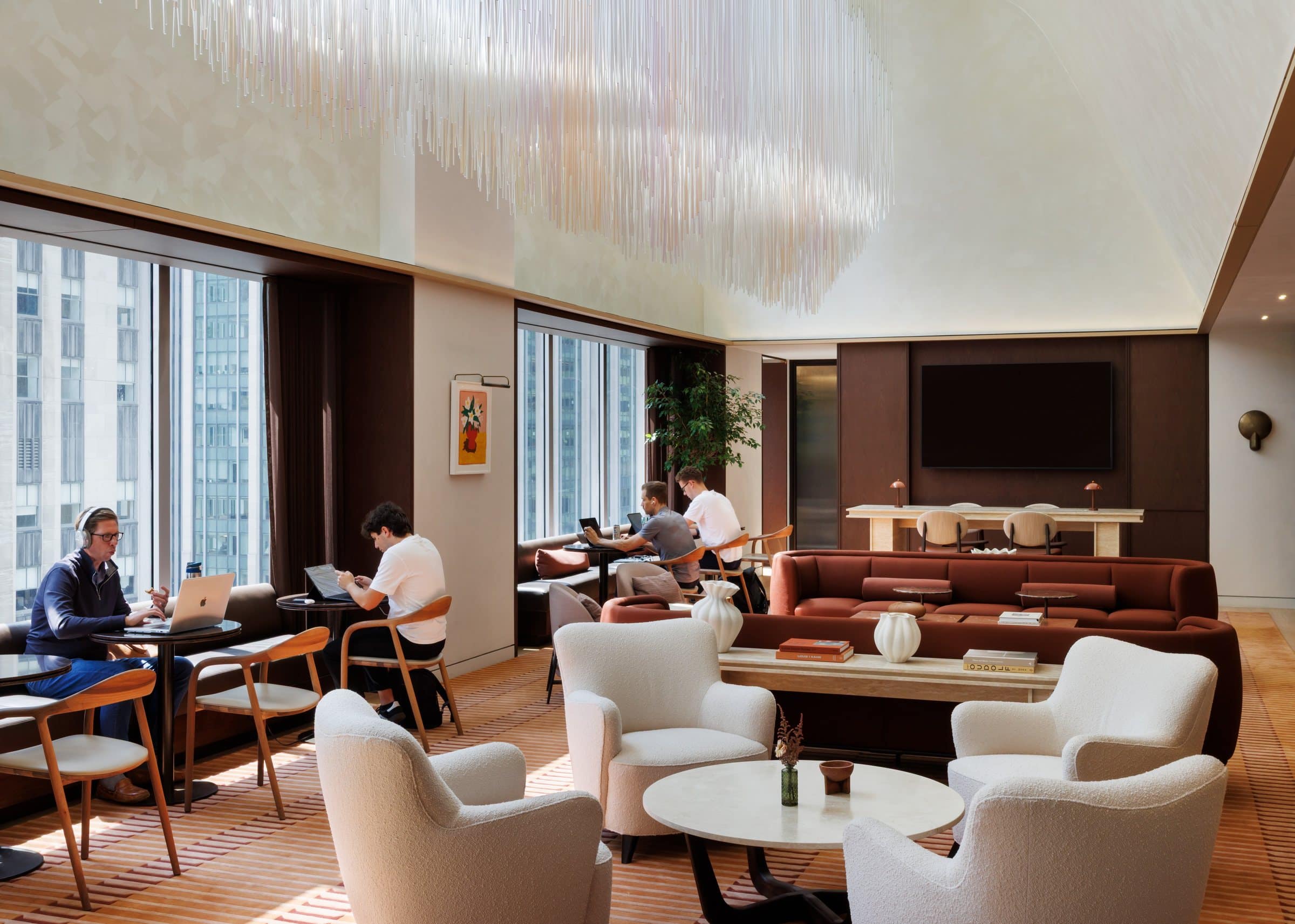 Side view of the hanging installation over pale lounge chairs and people working at window-side tables