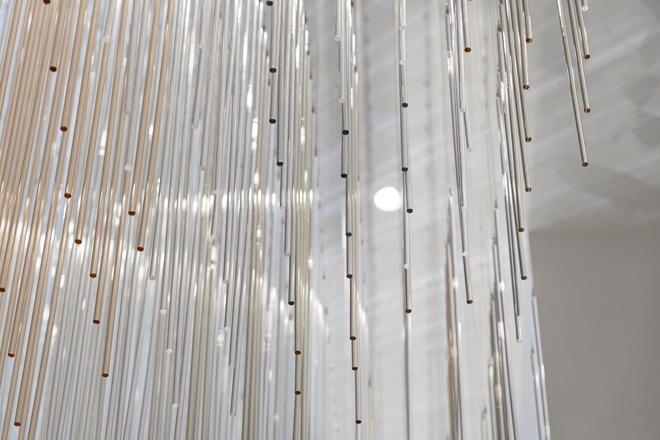 Close view of transparent hanging rods with small metallic tips catching the ceiling lights