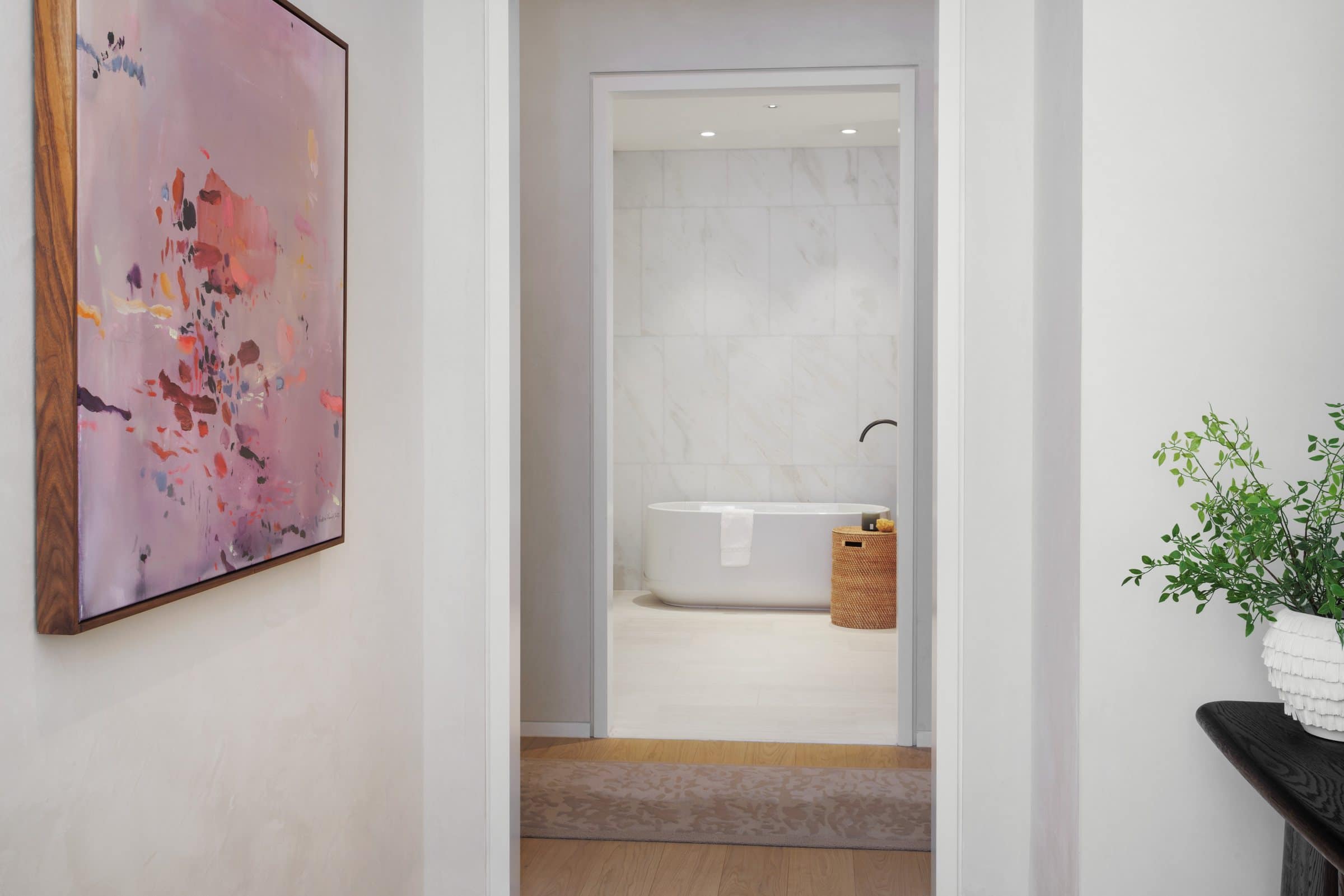 Mauve abstract painting with red and orange marks beside an open doorway to a bathroom