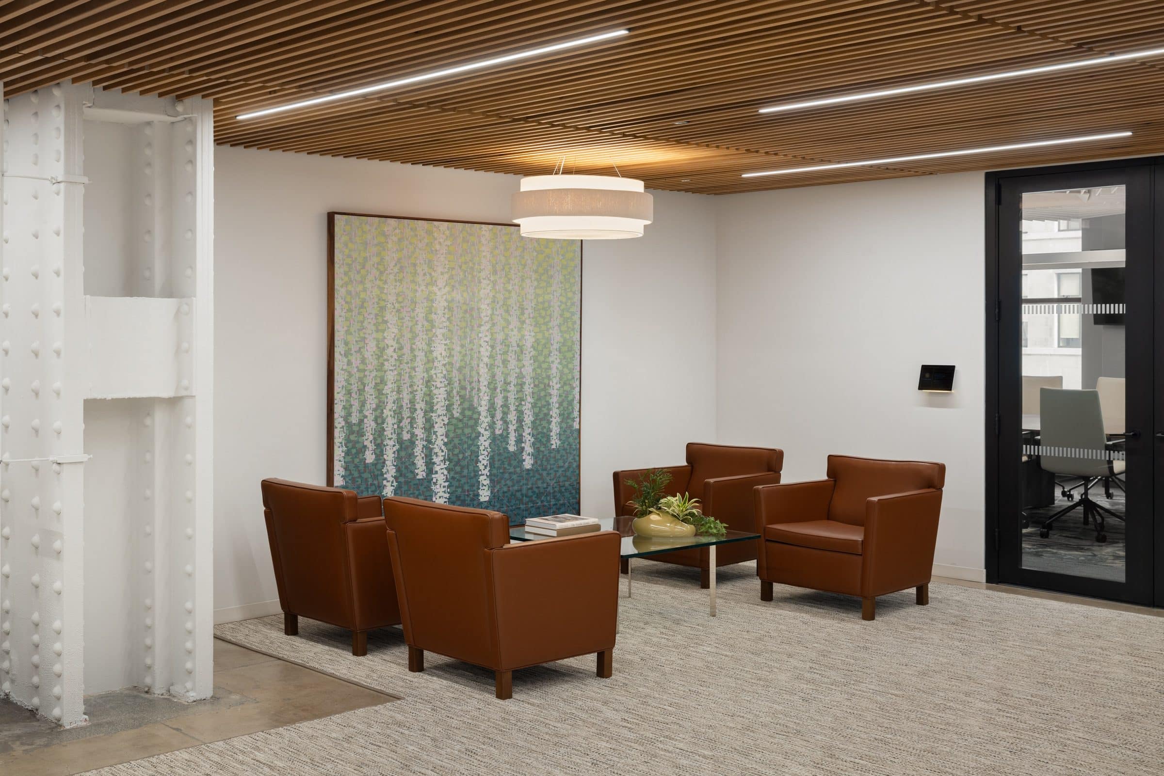 Tall painting of pale cascading marks over a green and blue field behind leather lounge chairs under a wood-slat ceiling