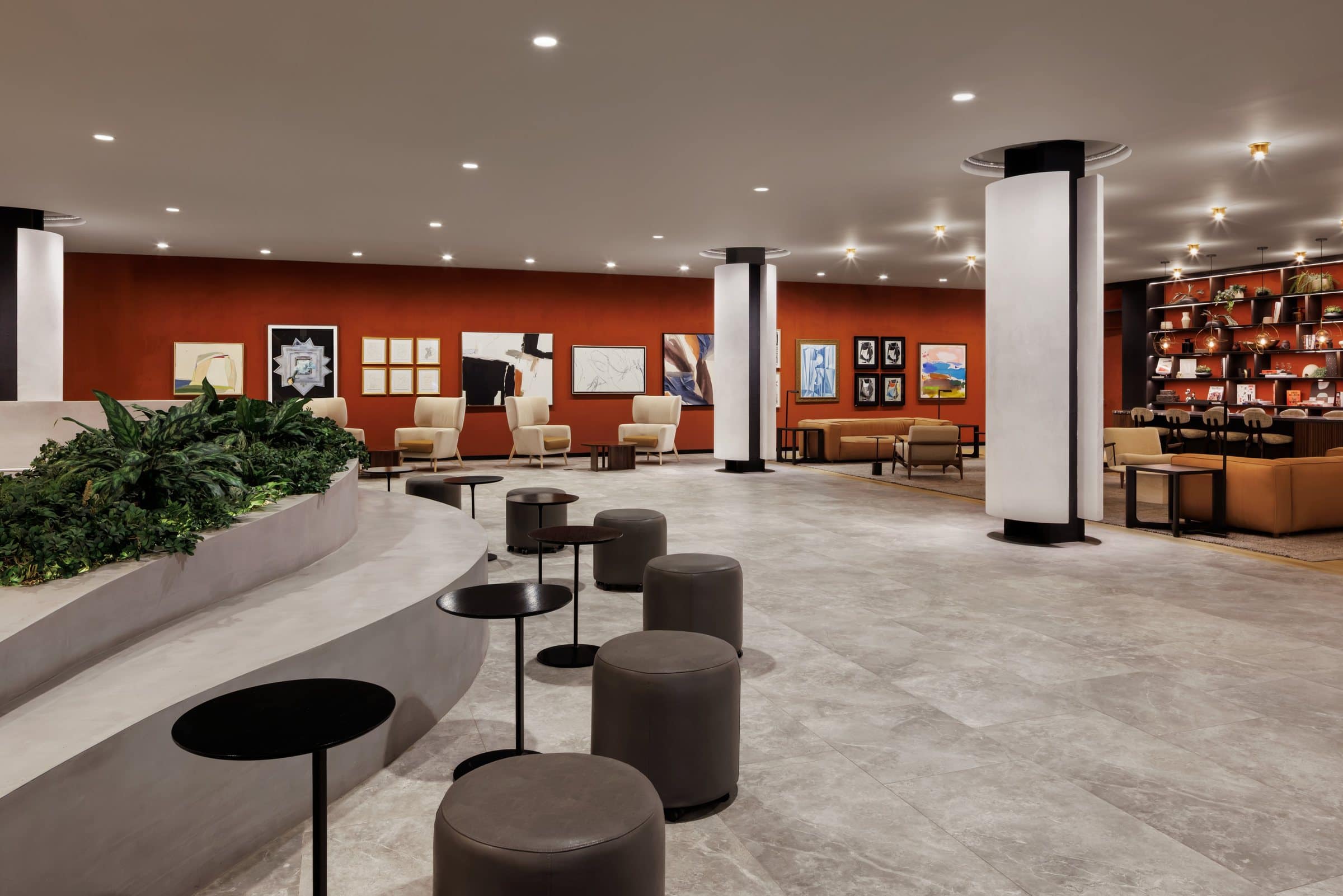 Paintings, photographs and small framed drawings line a rust-colored gallery wall behind lobby seating