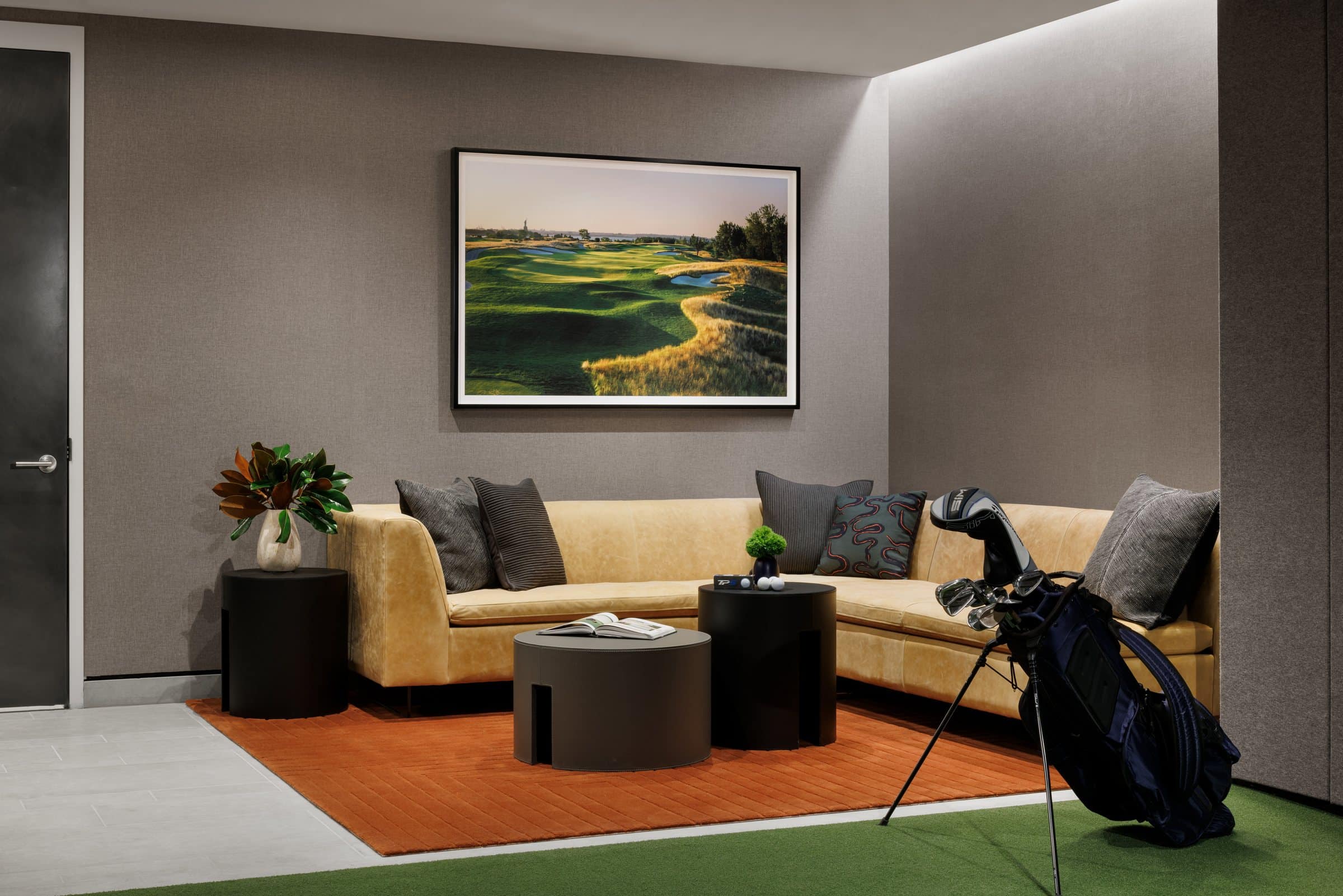 Golf lounge with a yellow sofa, a golf bag and a framed photograph of a sunlit golf course