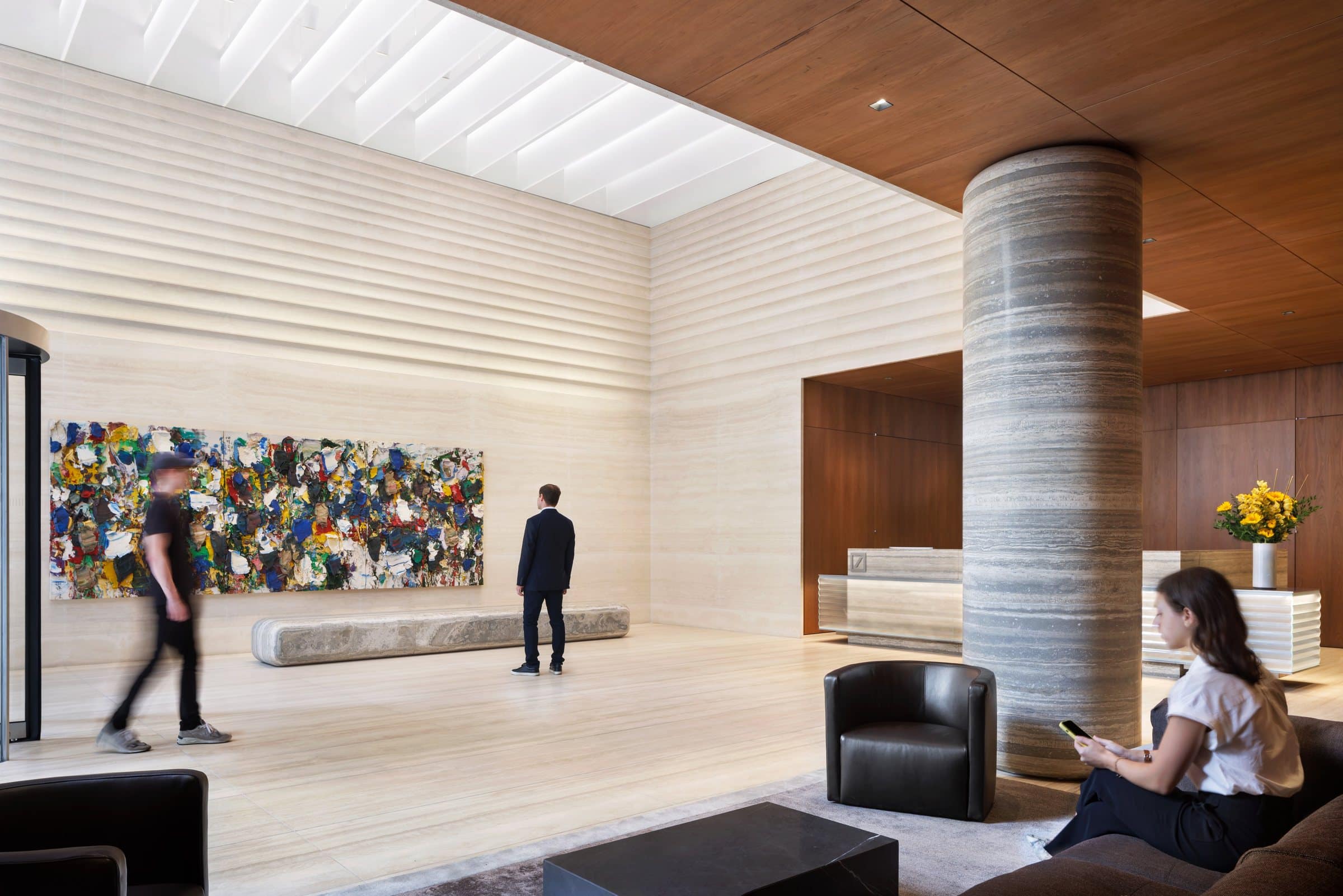 Visitors in the lobby seating area, with a striped stone column and the colorful painting beyond