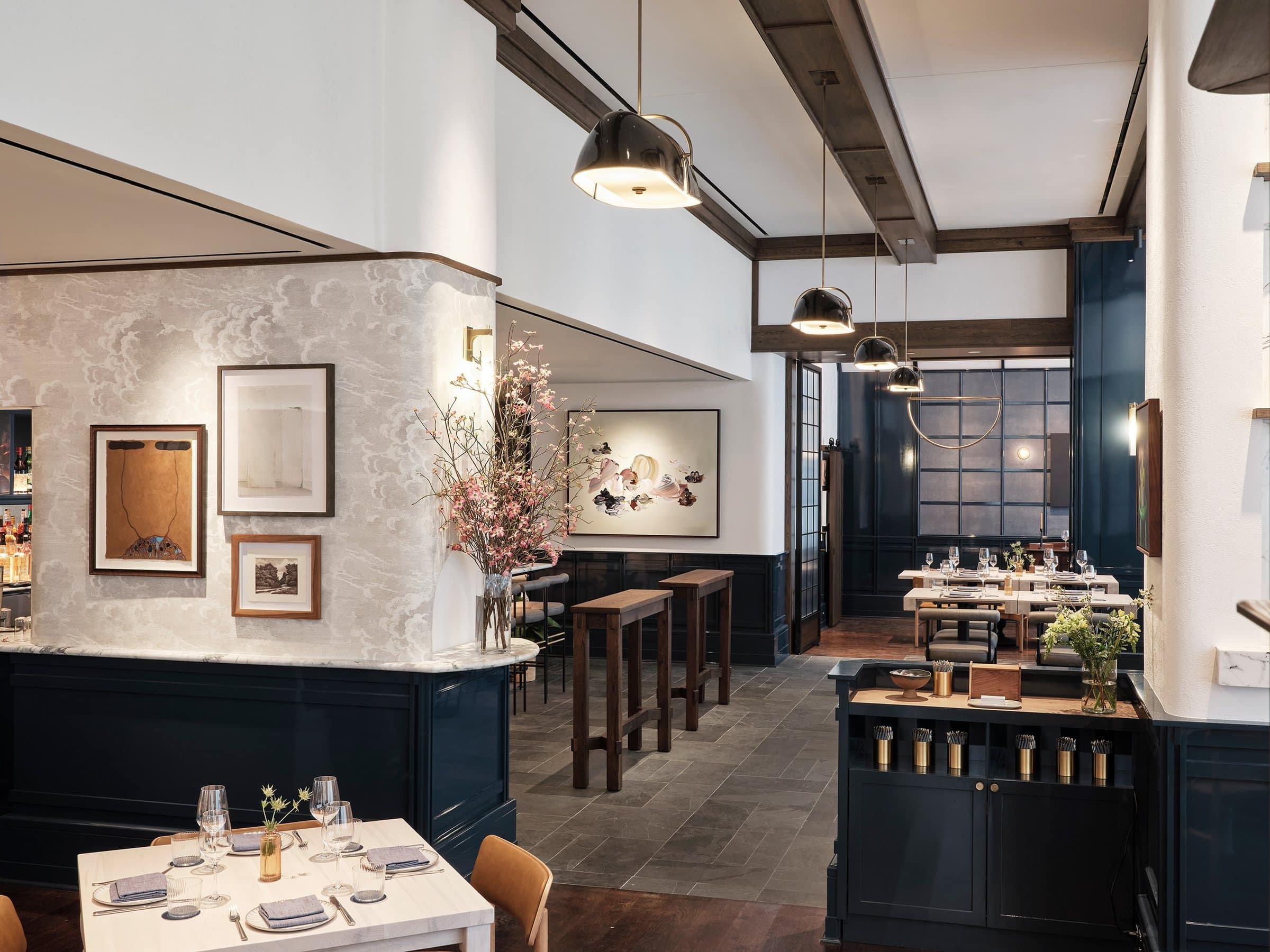 Greywind dining area with three framed works on a cloud-patterned pier and a large gestural abstract beyond the high tables
