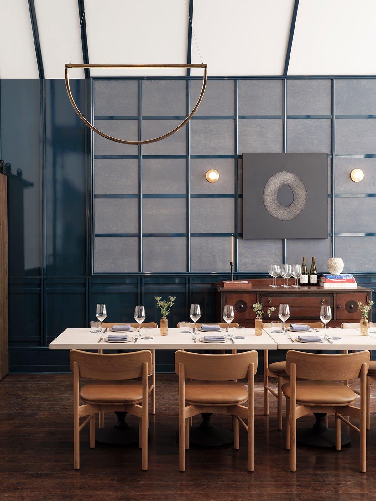 Private dining room with blue-paneled walls and a square gray artwork containing a textured ring above the credenza