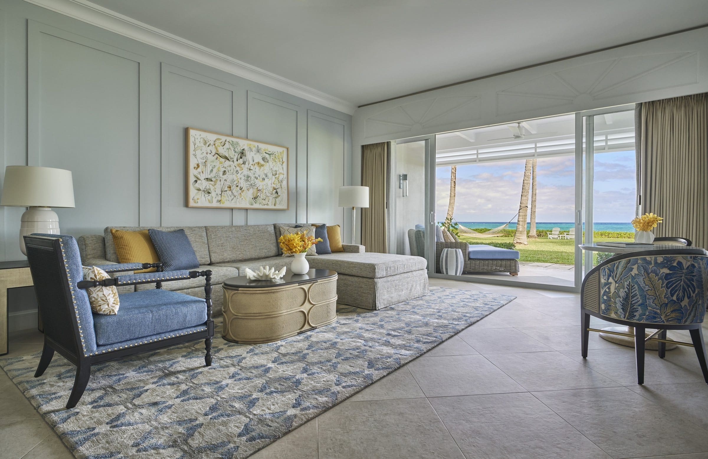 Ocean-view suite living room with a sectional sofa beneath a wide framed botanical composition