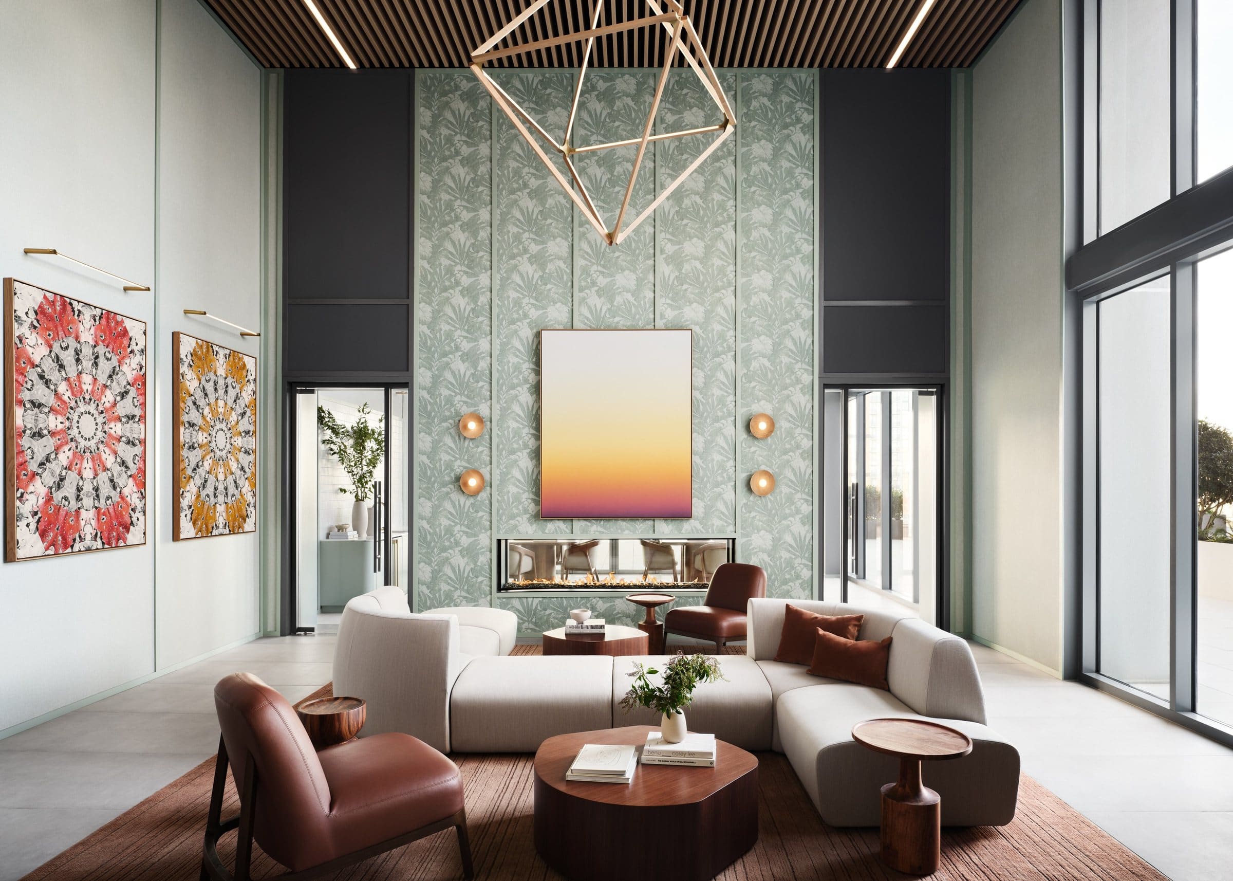 Double-height amenity lounge with a gradient painting above a fireplace and two red and yellow mandala paintings on the left wall