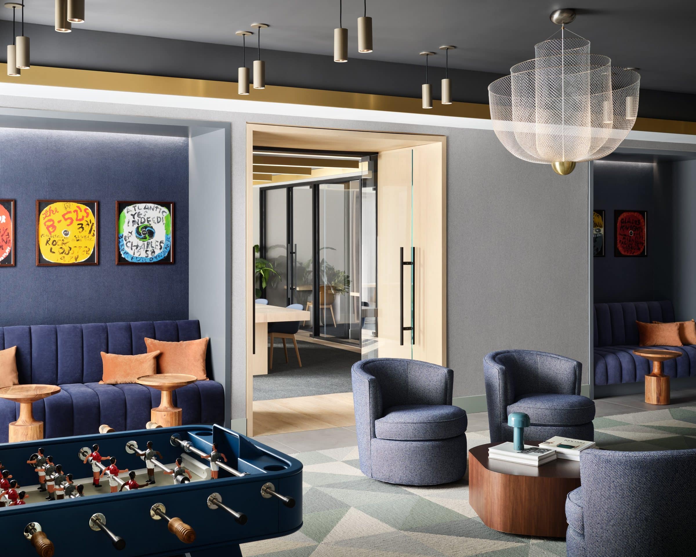 Games room with a foosball table, blue seating and colorful paintings of record labels above the banquettes