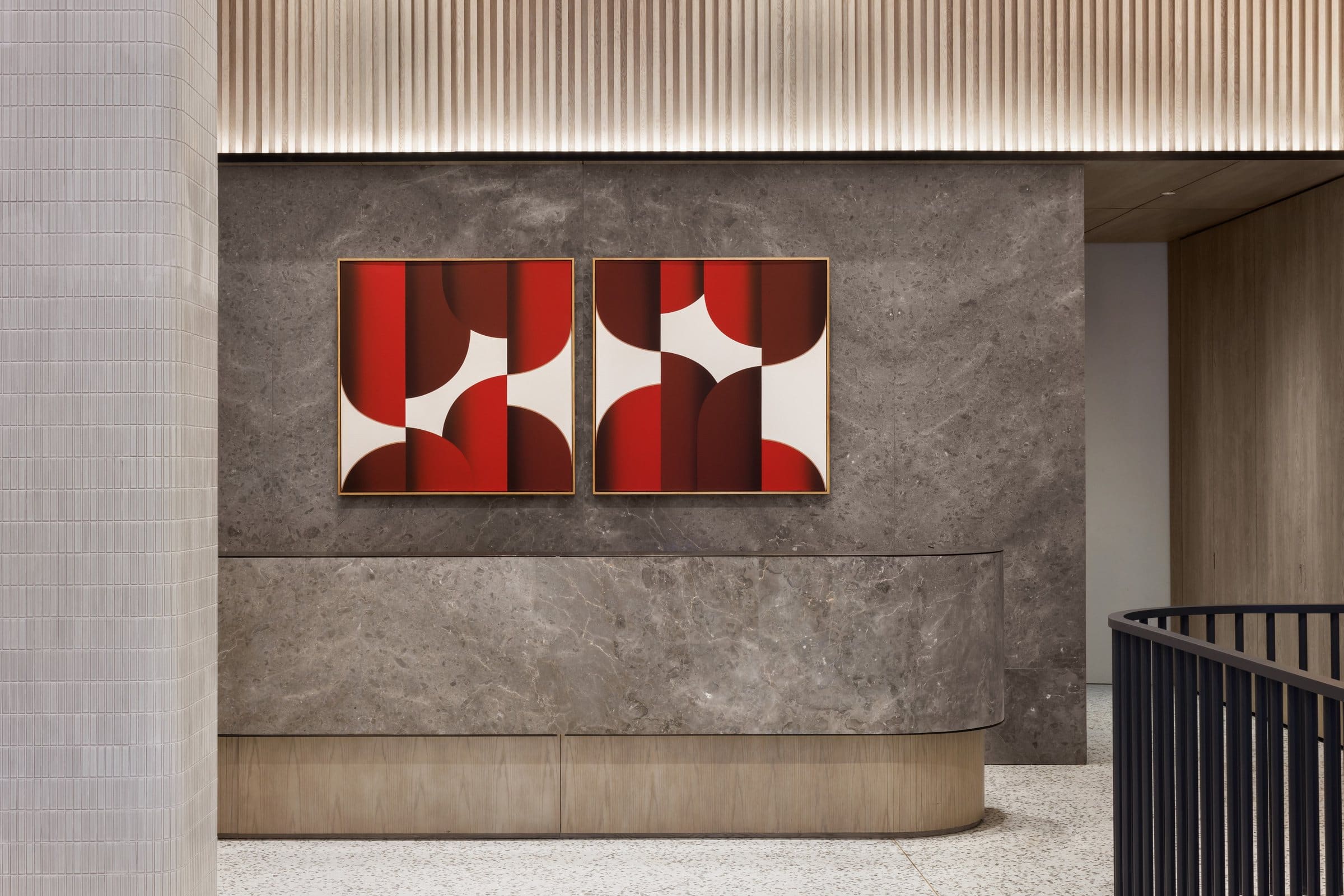 Two red, burgundy and white geometric canvases above the curved stone reception desk