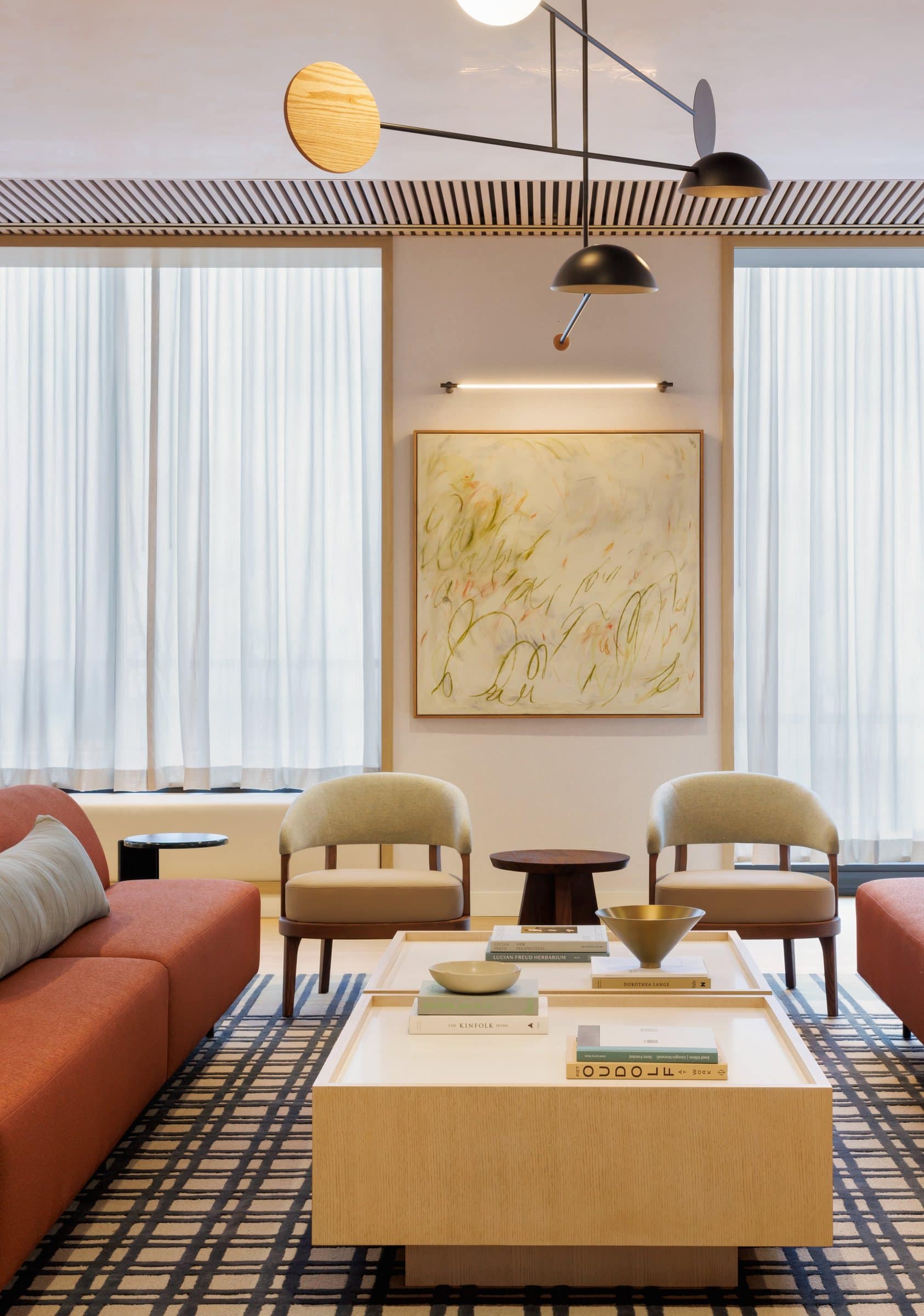 Cream armchairs beneath a pale green gestural painting in a sunlit lounge