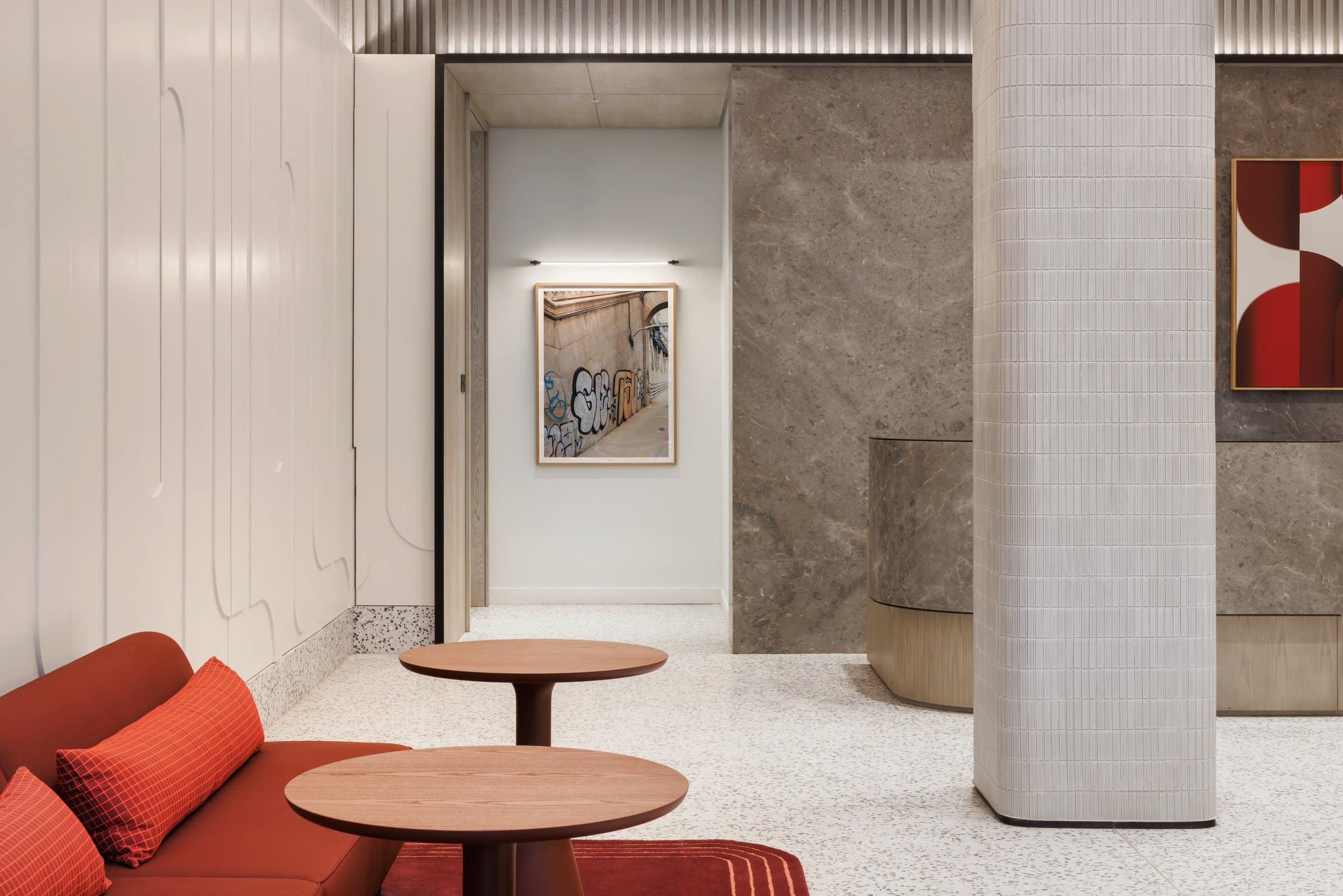 Lobby seating looking toward a framed street-wall photograph, with part of the red geometric diptych at right