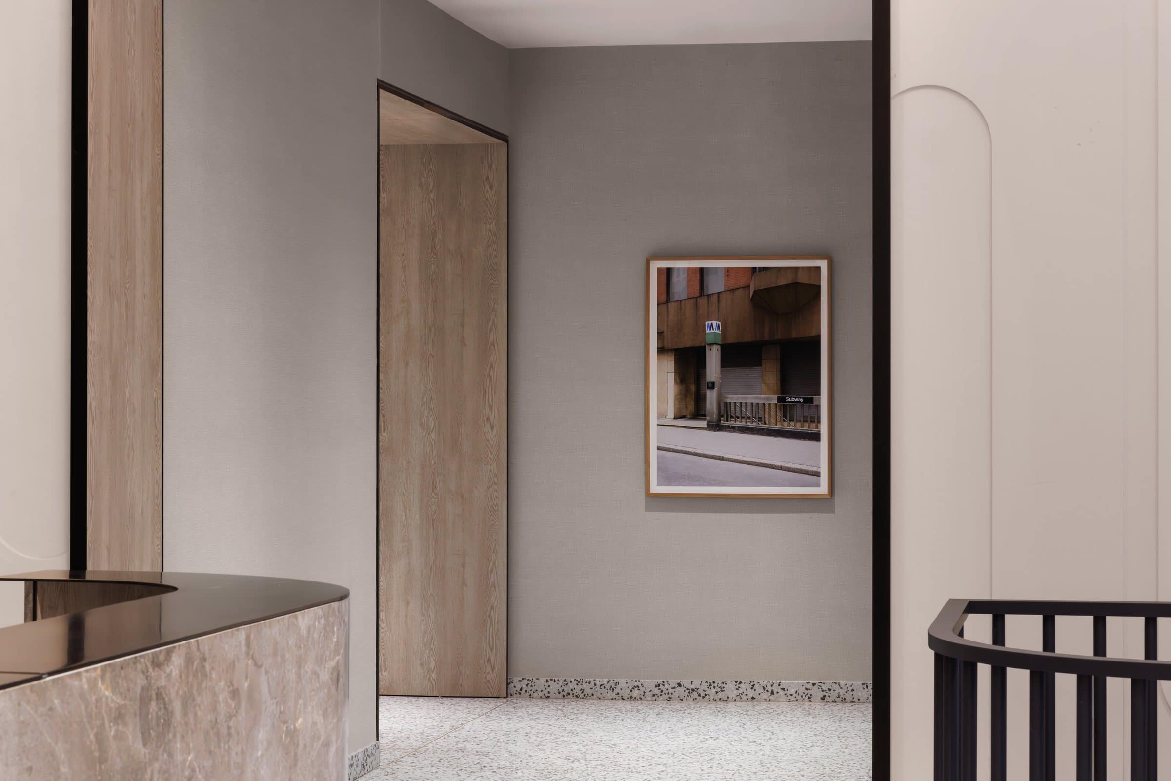 A framed photograph of a subway entrance on the wall beyond the stone reception desk
