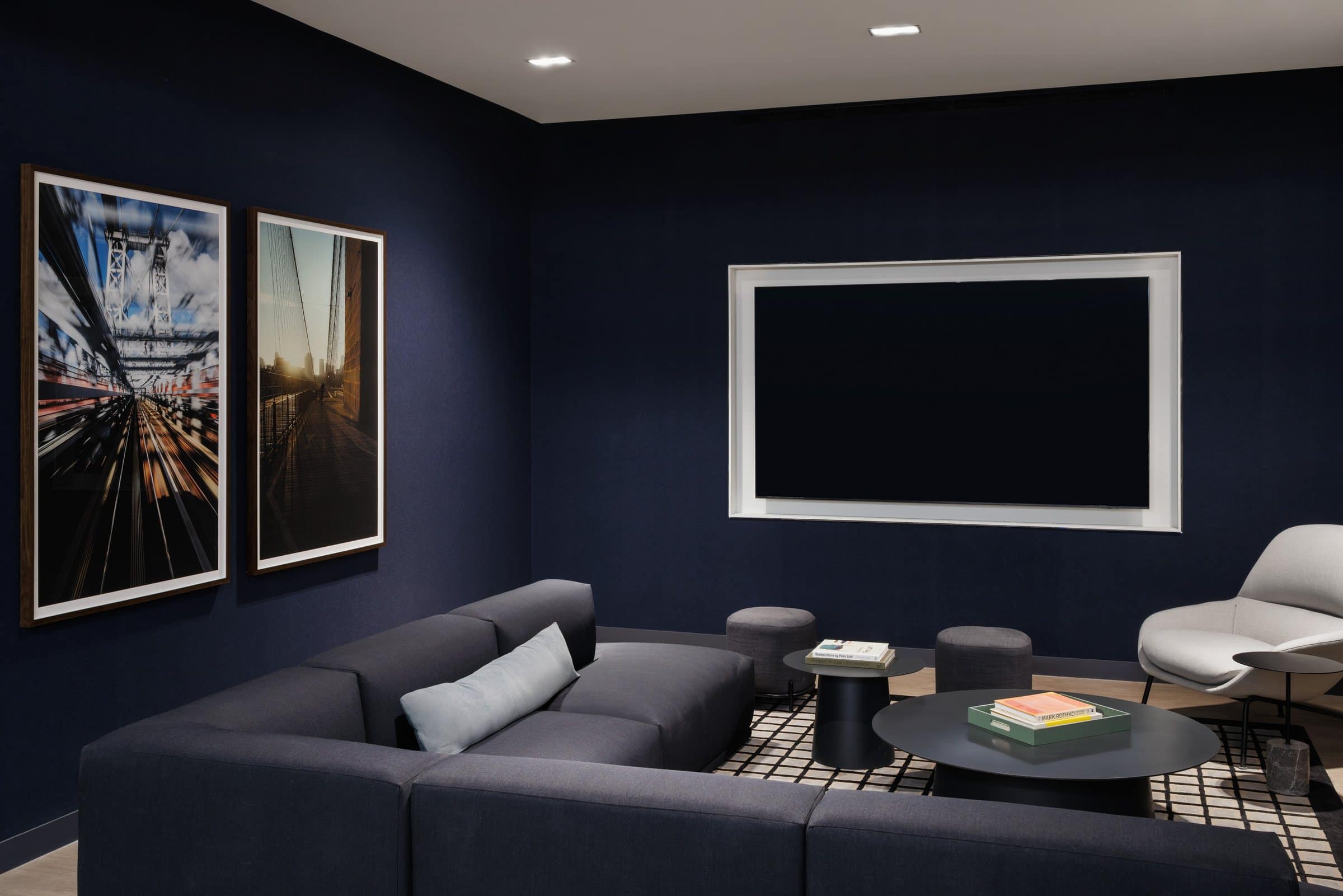 Dark media room with two framed bridge photographs above a blue sofa
