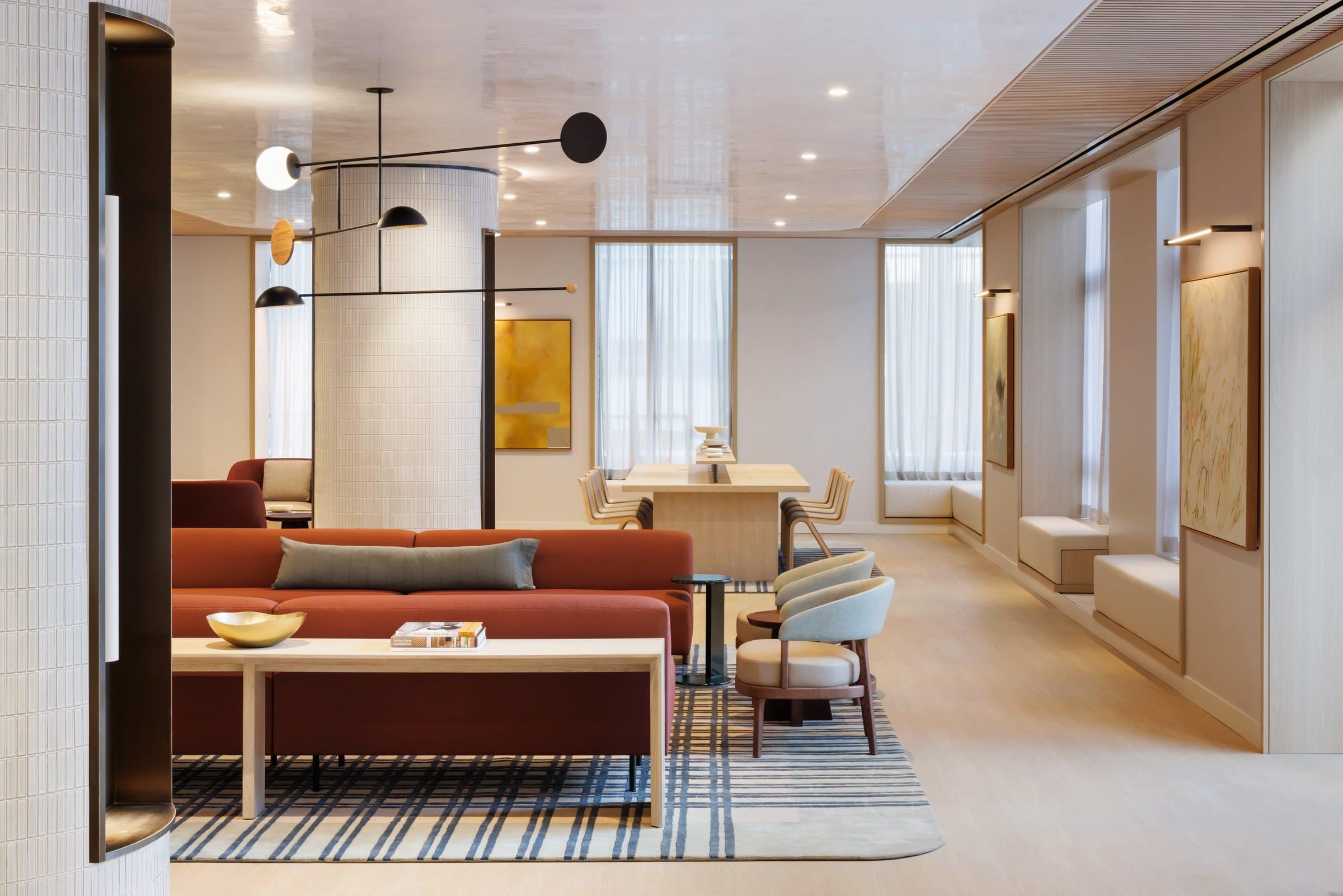 Wide lounge view with rust sofas, a yellow geometric painting and part of a pale green gestural painting