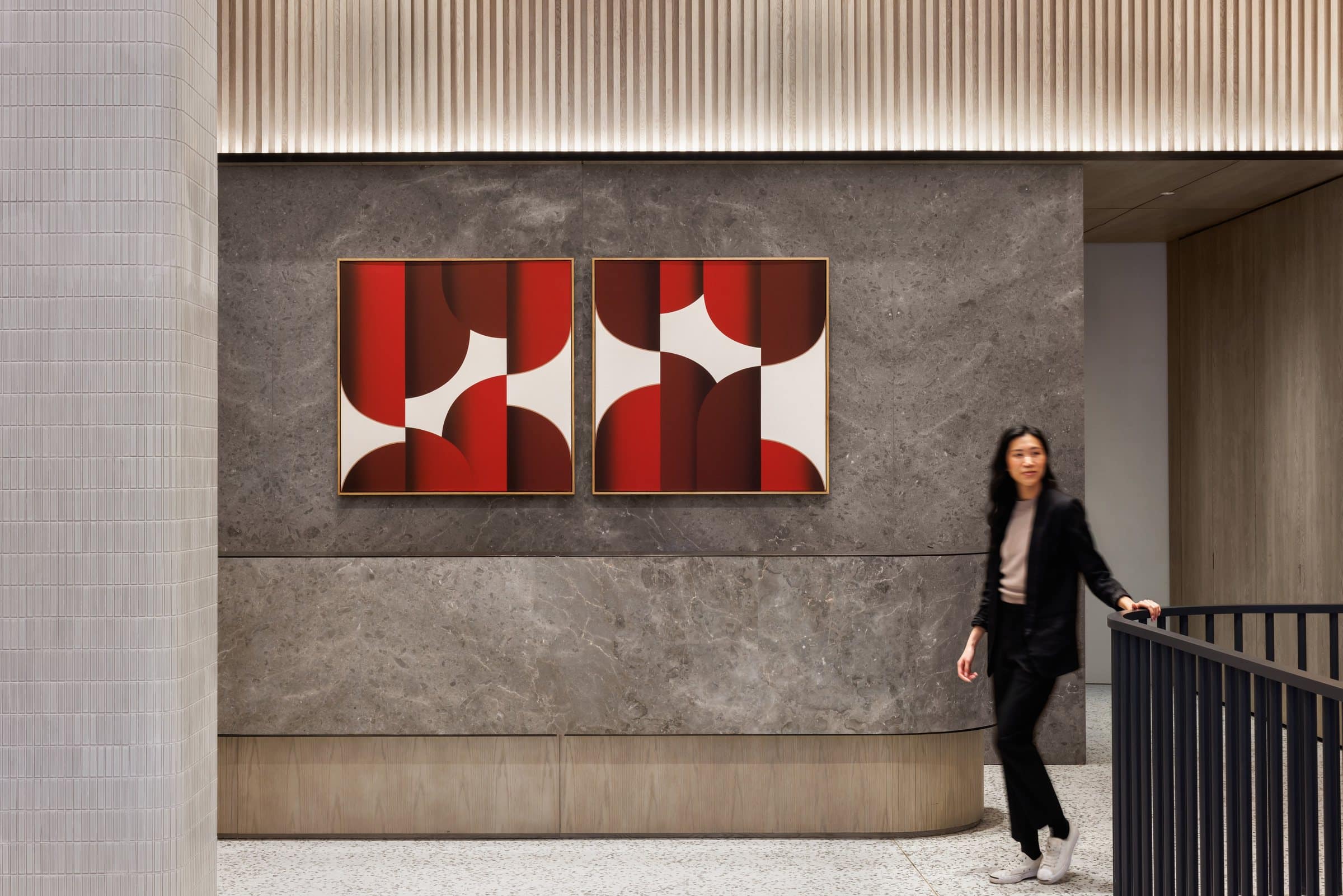 A visitor crosses the reception area beneath the red, burgundy and white geometric diptych