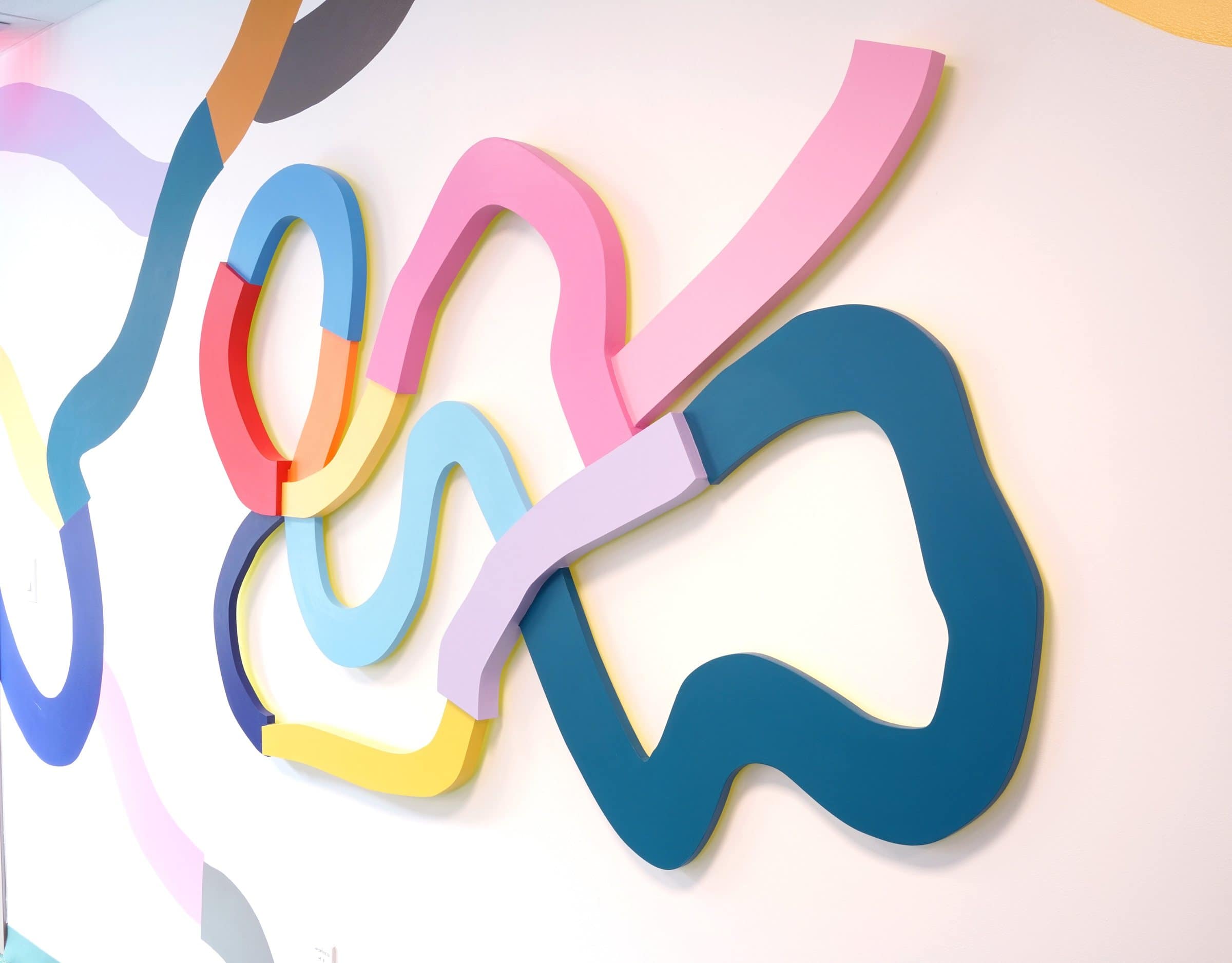 A close view shows painted wooden loops projecting from a mural wall at Harriet Tubman Supportive Housing Building.