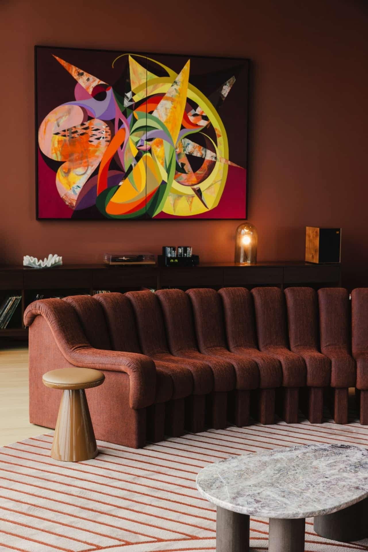 A multicolored abstract collage above the curved sofa in Linea’s listening room.
