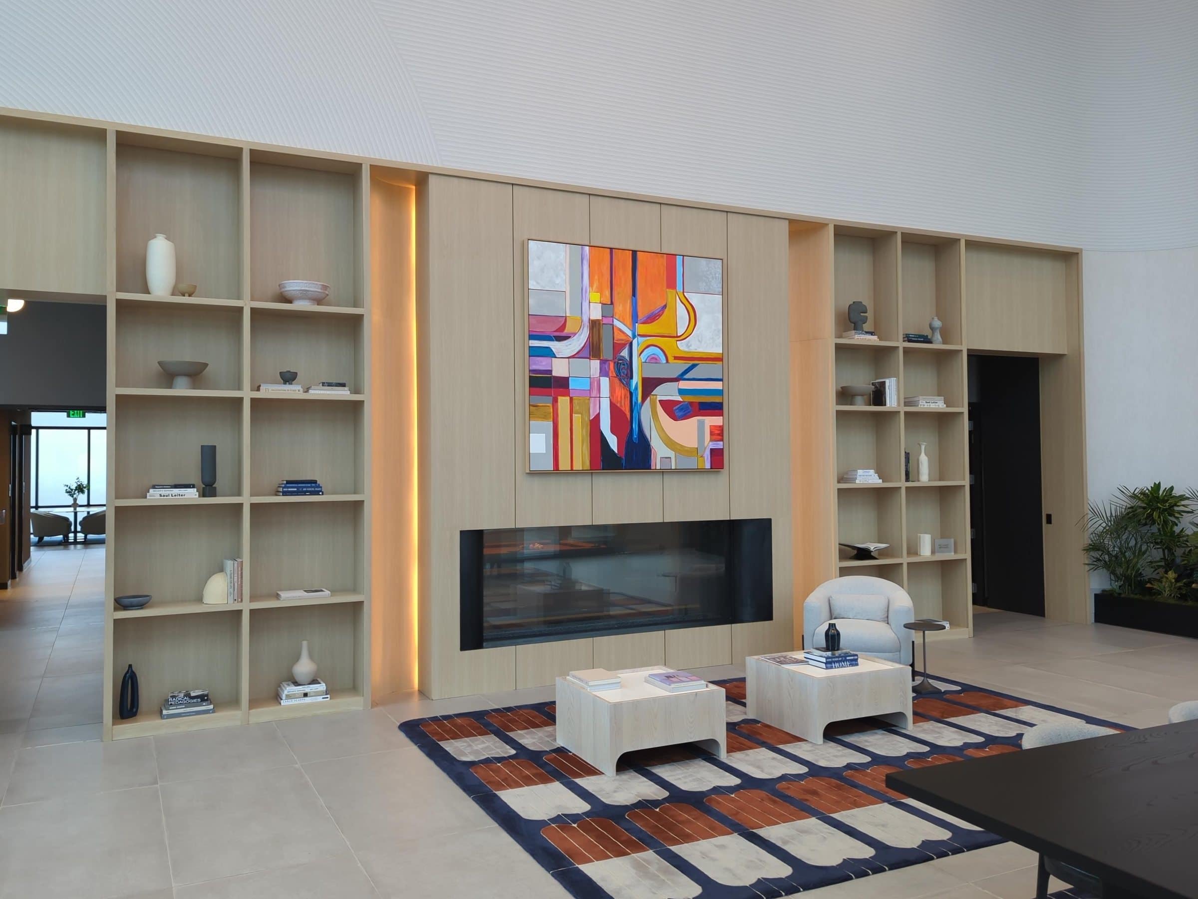 A geometric painting in orange, pink and blue above the fireplace in a bright Linea lounge.
