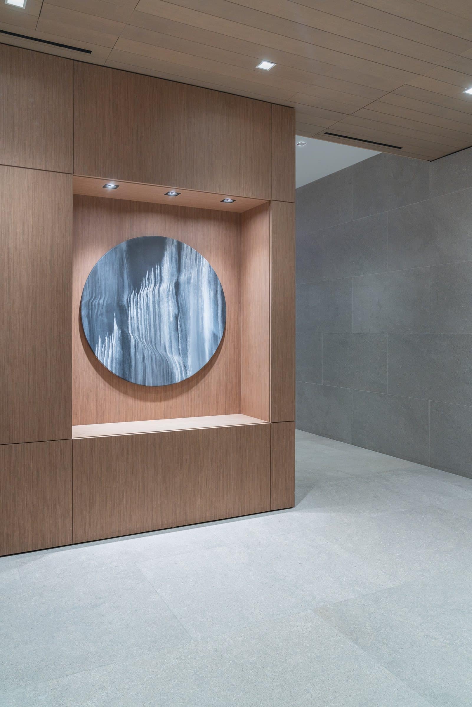 Circular blue-and-white abstract work mounted in a spotlit wood-paneled niche