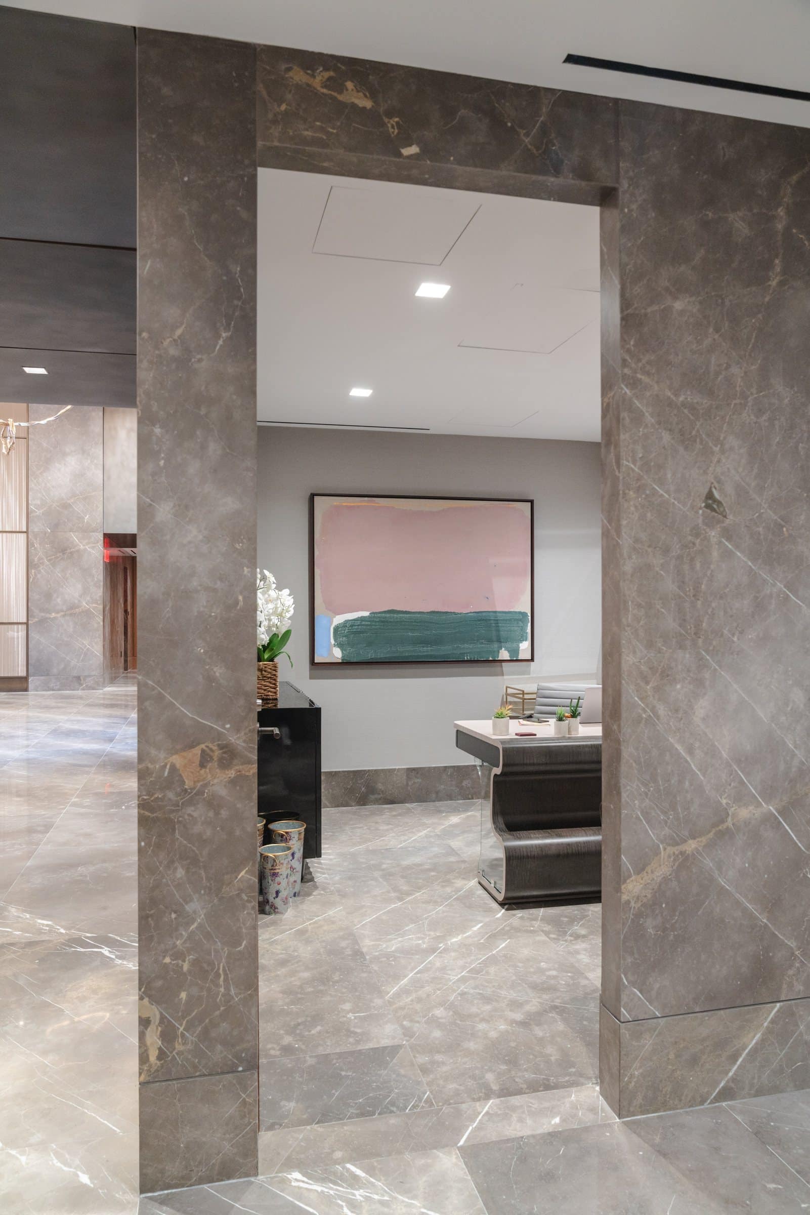 Stone-framed doorway toward a pink, cream and green color-field painting above a reception counter