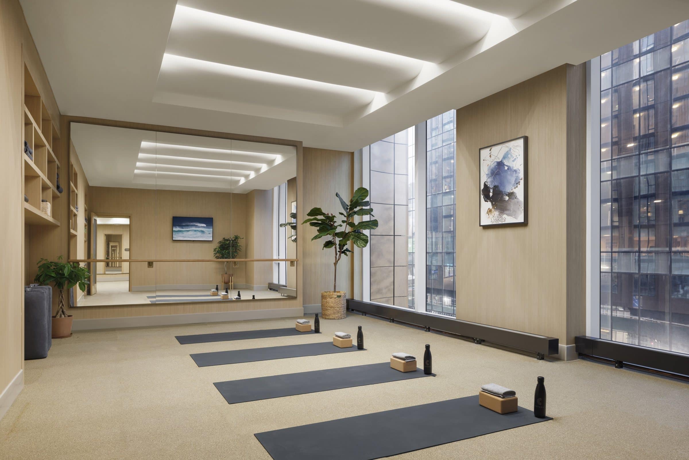 Yoga room with mats and a mirror, with a blue-gray abstract work between tall windows