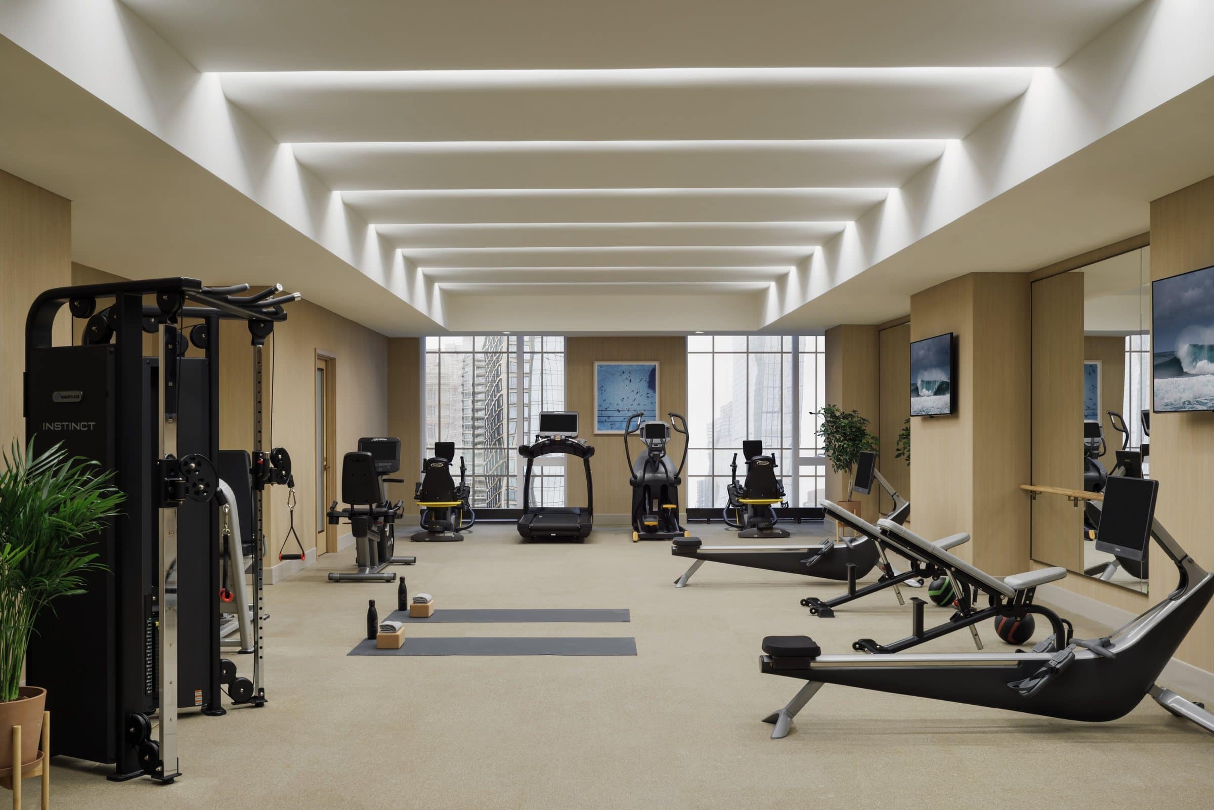 Fitness room with rowing and cardio equipment, a blue pool photograph and smaller sea photographs