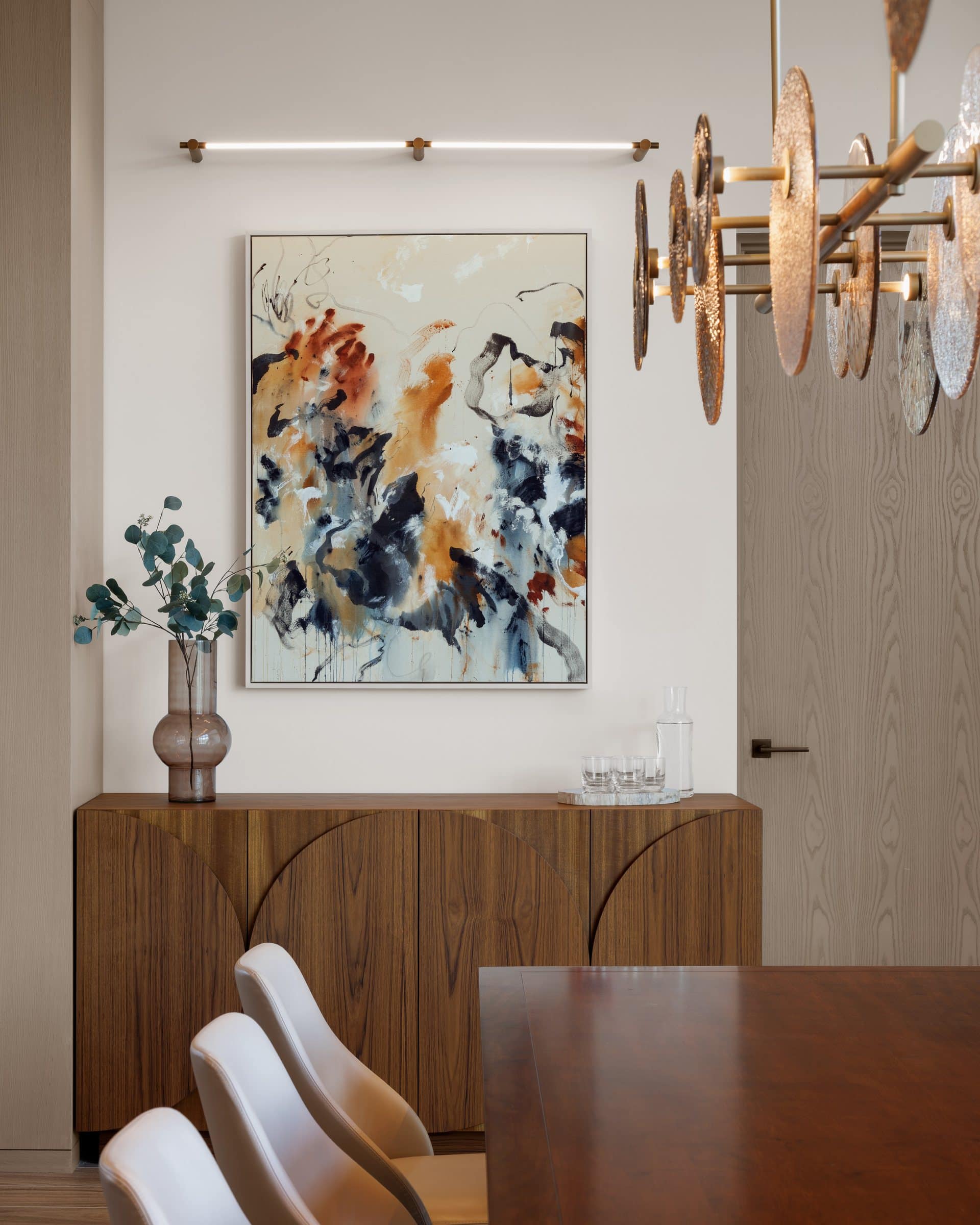 A cream, orange and black gestural canvas above a sideboard at the end of a private dining room
