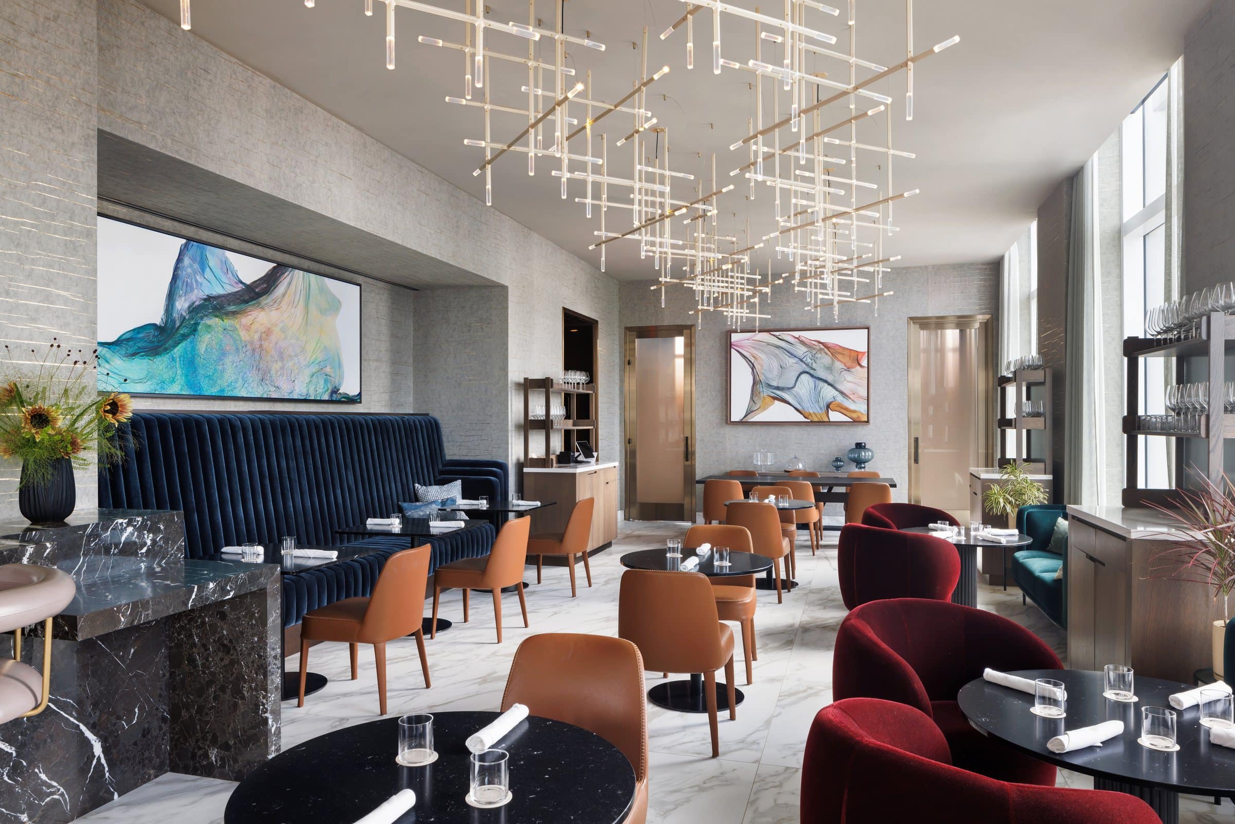 Dining room with a blue banquette beneath a wide teal and violet layered abstract, and a second work on the back wall