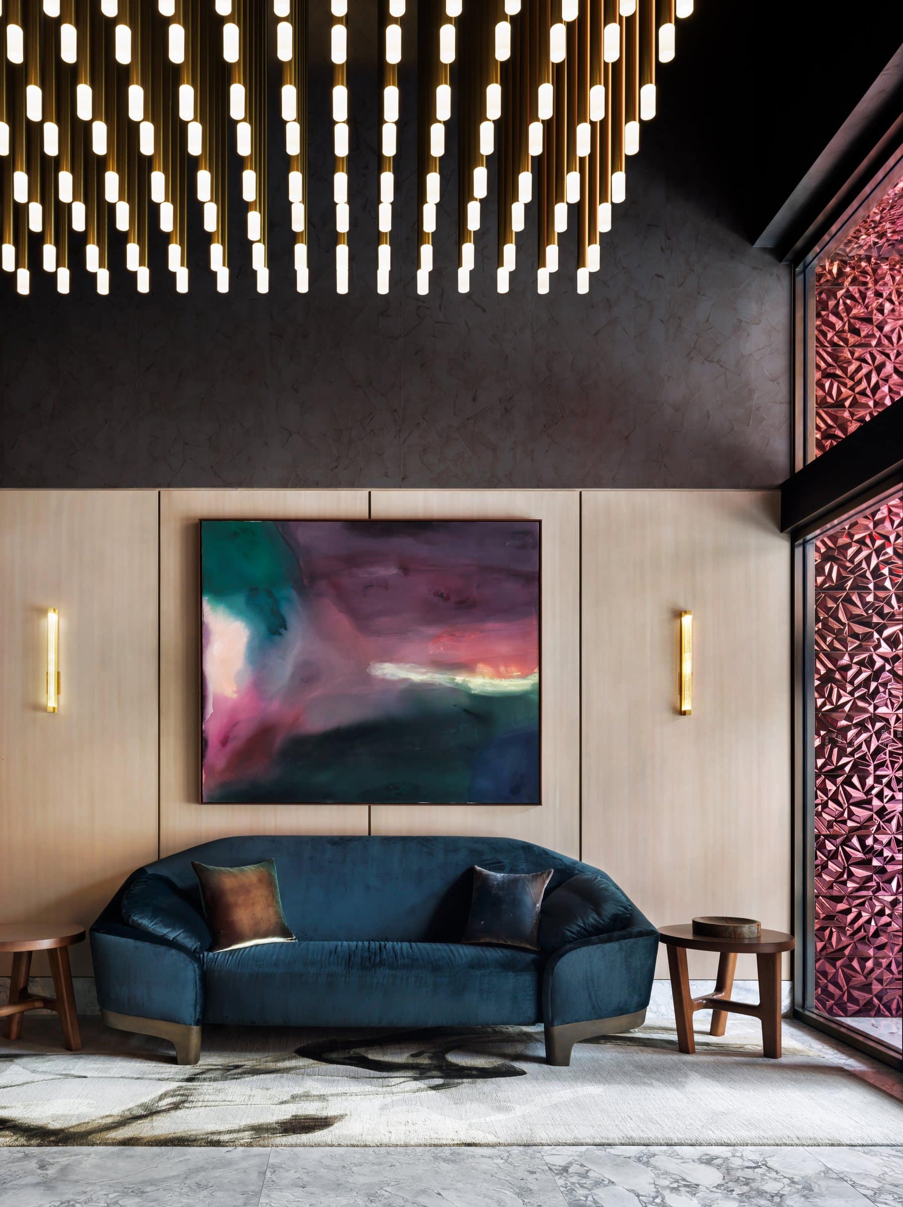 Teal velvet sofa beneath a large plum, green and pink abstract painting in the lobby