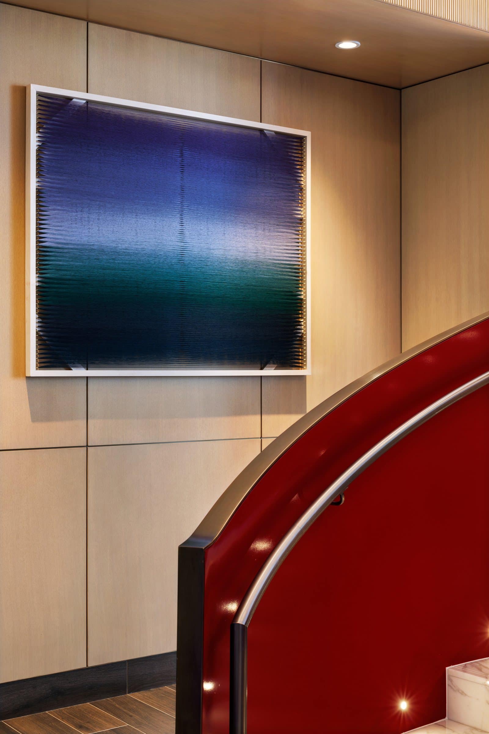 Close view of a framed violet-to-green thread work above the red spiral stair balustrade